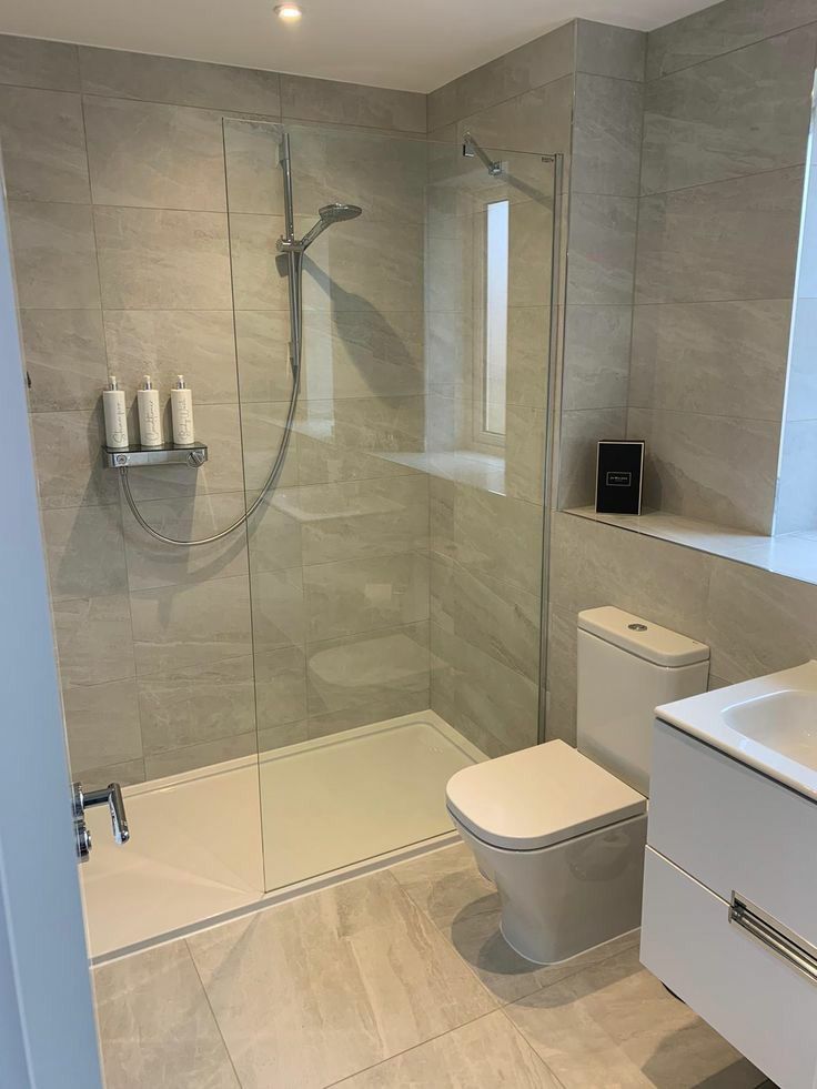 Modern shower enclosure with stone-look tiling, toilet and vanity