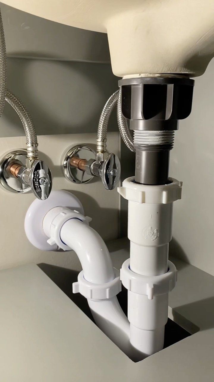 Neat basin waste trap and chrome isolation valves under a vanity