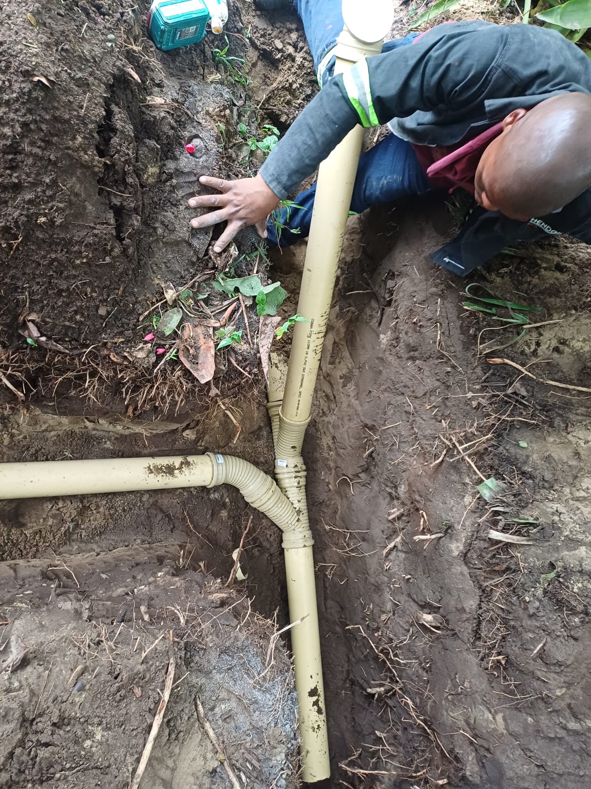 New underground PVC drain junction and bends being fitted in a trench